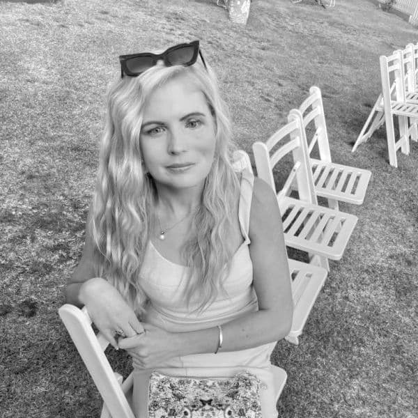 Tina a Moyai user sitting on a white folding chair dressed up for a the races