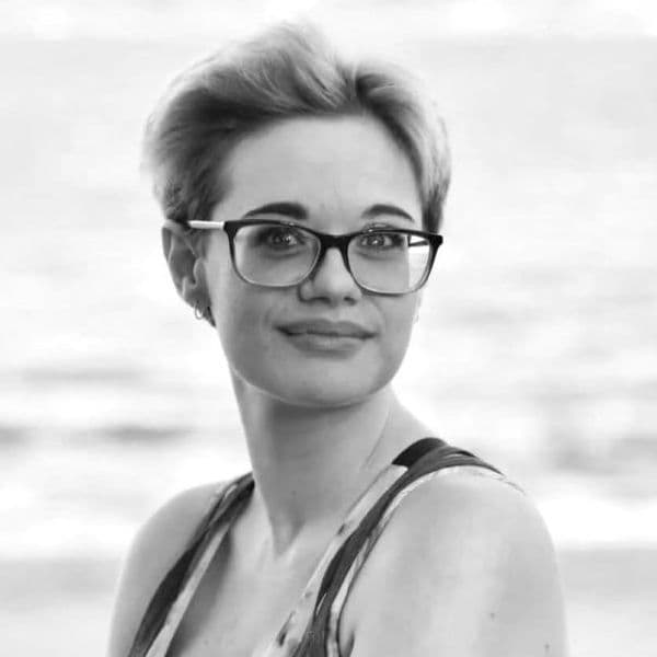 A lady with short hair and a warm smile facing the camera.